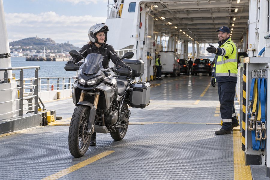 Motorradfahrerin fährt auf der Fährrampe an Bord